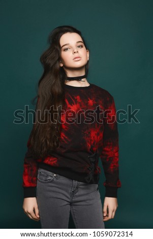 Young brunette teen model girl posing at dark-green background
