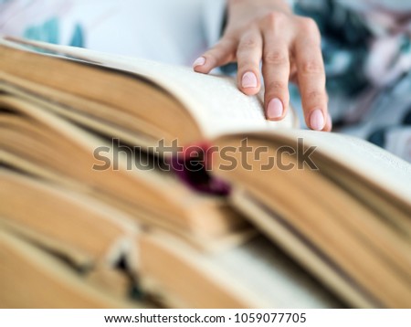 Female hand with a lot of open books.