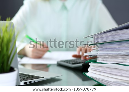 Bookkeeper or financial inspector  making report, calculating or checking balance. Binders with papers closeup. Audit and tax service concept. Green colored image background  Royalty-Free Stock Photo #1059078779