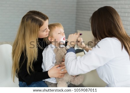 Doctor examine child's throat. Boy and mother at pediatrician office.