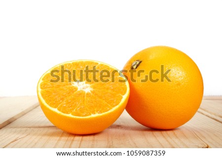 Yellow oranges with Half cut orange,  are sweet and sour. Popular to make juice. Drink to quench thirst, Put on wooden floor on the white background.