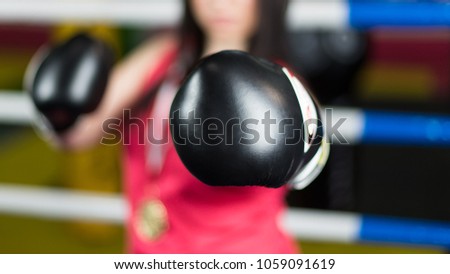 Blurred background. Girl boxer with a medal of the winner stretched out his hand Boxing gloves black