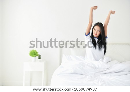 Lifestyle Concept. Cute Asian girl in night dress. Beautiful asian woman is relaxing in a white bedroom. Beautiful asian woman  is sleeping in the morning.