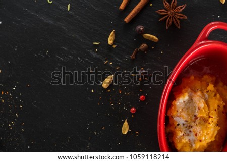 Pumpkin porridge with millet in original, stylish ceramic forms on the black chalkboard,shale stone with indian spices and herbs.Bio asian healthy food or cookingconcept. Close up, space for text