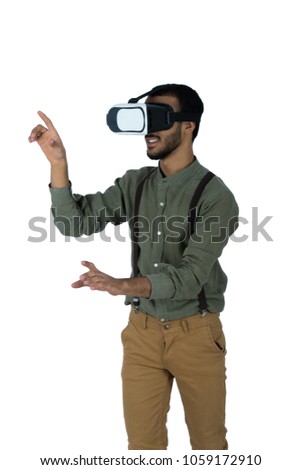 young man wearing VR glasses seeing something up pointing at it by his finger, isolated on white background
