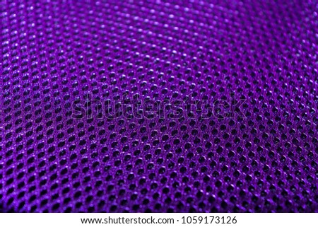 Violet Polyester texture. The breathable material. The holes for air. The back of the backpack. Blurred background. Space for text.