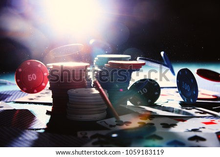 Chips and cards in the casino in the backlight. Poker chiips falling with back flash lighting. Royalty-Free Stock Photo #1059183119
