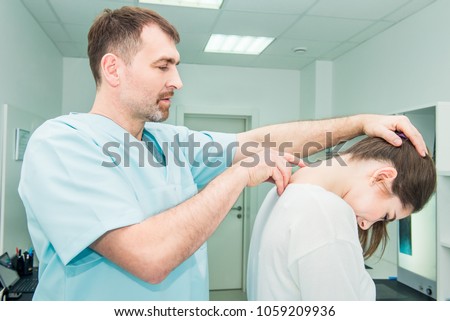 Male neurologist doctor examines cervical vertebrae of female patient spinal column in medical clinic. Neurological physical examination. Osteopathy, chiropractic, physiotherapy. Selective focus Royalty-Free Stock Photo #1059209936