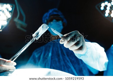 Surgery by a group of surgeons under a lamp in a dark room