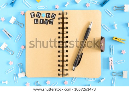 Beautiful picture from the top. Notepad on springs with an inscription To Do List. Chaotically scattered office supplies on a blue background.