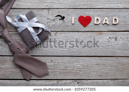 Happy Fathers Day card with male presents, love dad letters, present and tie on rustic wood background, copy space, top view