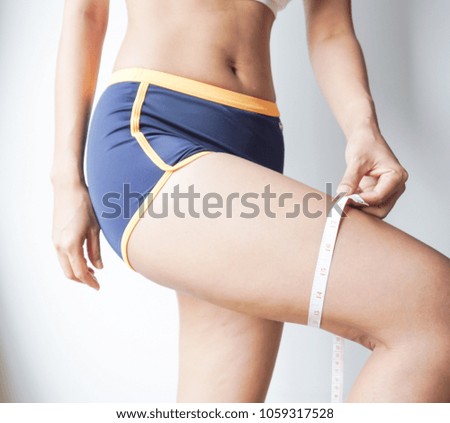 Young woman asian measuting her thigh with a measuring tape.
