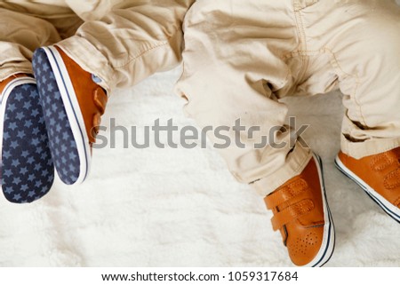Small legs of two newborn twins in panties and leather baby shoes on a blue background. Happy Family concept. Beautiful conceptual image of Maternity. Kids fashion