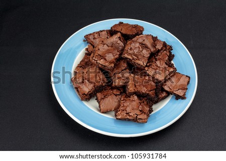 Brownies cut in to squares lying on a plate with blue rim