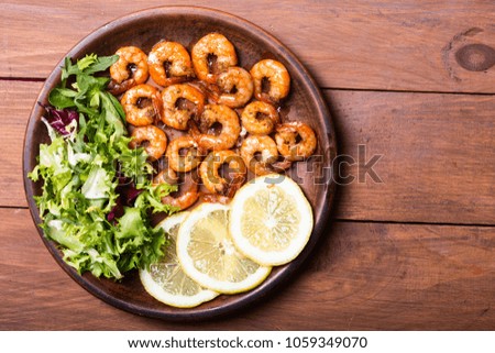 Salad with lattuce , lemon and shrimps . Seafood background
