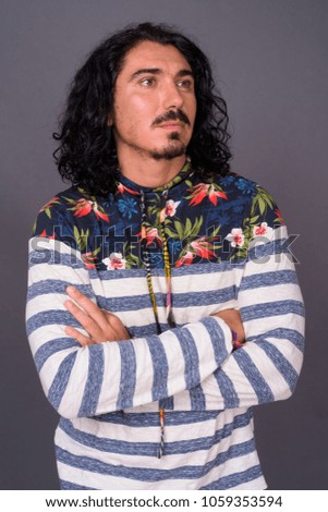 Studio shot of handsome man with curly hair and mustache against gray background