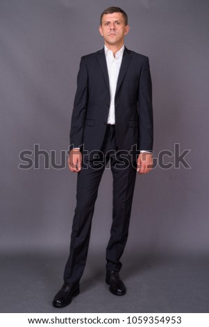 Studio shot of handsome businessman with short hair against gray background