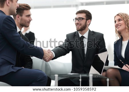 Partners concluding deal and shaking hands in the presence of team members