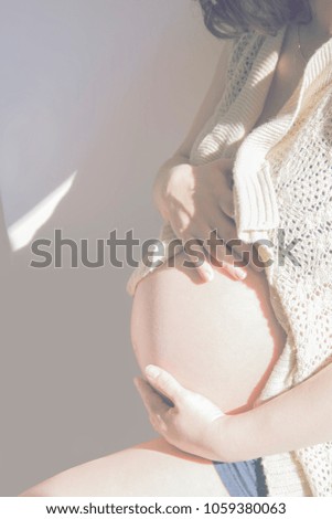 Beautiful pregnant woman future mom. Close-up abdomen, selective focus. Toning. Sunny day.  Motherhood. Girl silhouette