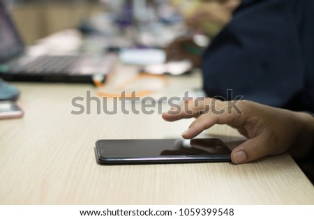 Photos of hands that are touching the screen of a smartphone during a meeting.