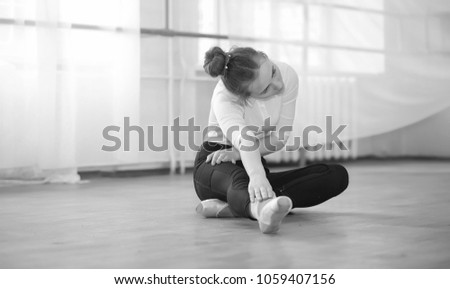 Young ballet dancer on a warm-up. The ballerina is preparing to perform in the studio. A girl in ballet clothes and shoes kneads by handrails.
