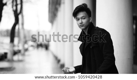 Black White photo of Asian young man outdoors posing at camera