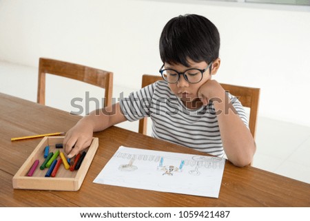 Happy Asian kid sit on the wood chair and paint zoo cartoon with crayon color