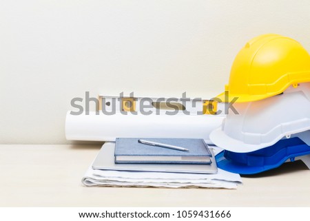 Engineering and construction concept. Helmets, blueprint and accessories on table with white wall background. Picture for add text message. Backdrop for design art work.