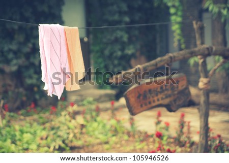Laundry hanging outside on string clothing line in front yard of traditional rural Chinese home with fresh washed towels 