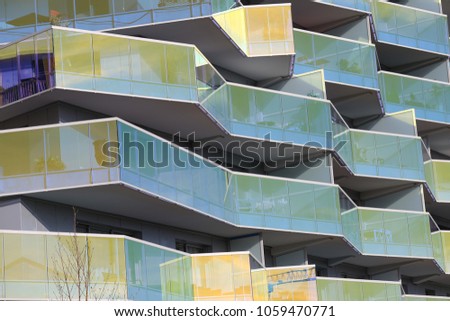 Close up outdoor view of a modern building facade made of yellow reflective mirrors attached to the balconies. Pattern of geometric shapes and lines with shadows. Abstract architectural design.  