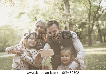 Smiling father taking self picture of family in nature.