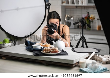 Young woman with professional camera taking food photo in studio