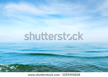 Blue sea water with waves and white clouds on the sky. Calm tropical landscape