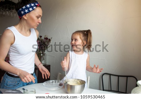 Mother helps daughter in the kitchen, cooking the cookie
