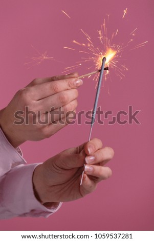woman set fire to bengal light on pink background. Christmas and newyear party sparkle