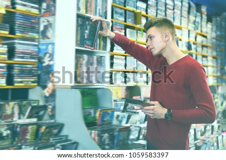 Nice man browsing contents on DVD cover choosing movies from diversity at store