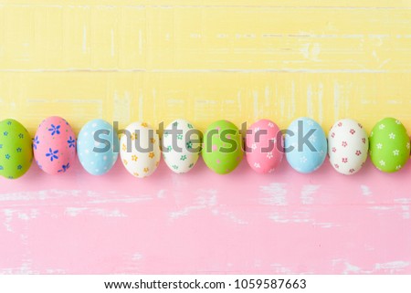 Happy easter! Row Easter eggs with colorful paper flowers on bright pink and yellow wooden background.
