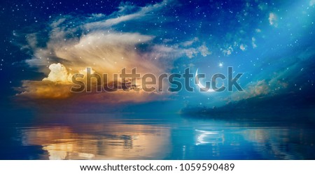 Ramadan Kareem background with crescent, stars and glowing clouds above serene sea.  Elements of this image furnished by NASA Royalty-Free Stock Photo #1059590489
