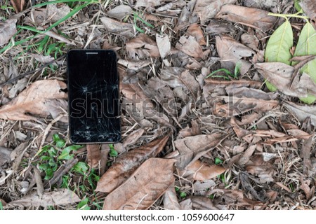 Broken smartphone lost in the grass of a meadow