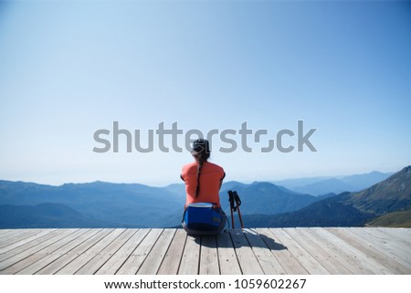 Female tourist sitting on edge of wooden bridge
