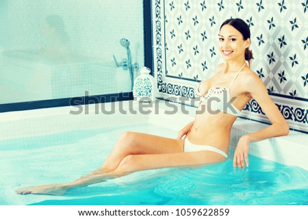 Happy positive cheerful girl in swimwear enjoying and relaxing in jacuzzi at spa hotel