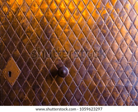 Antique metal door with carved romboid diamond pattern, the doors has a keyhole and a central doorknob