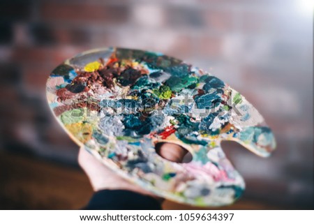 Multicolored palette in the hands of the artist.