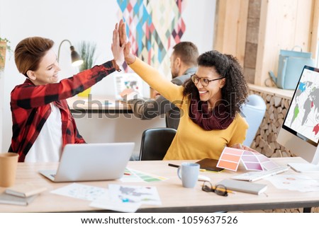 Well done. Good-looking inspired young smart women smiling and giving a high-five while working in the office Royalty-Free Stock Photo #1059637526