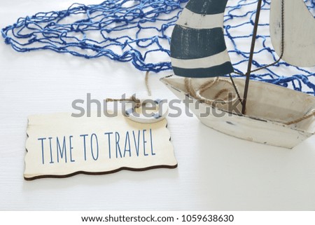 nautical concept image with white decorative sail boat and text over wooden board: TIME TO TRAVEL