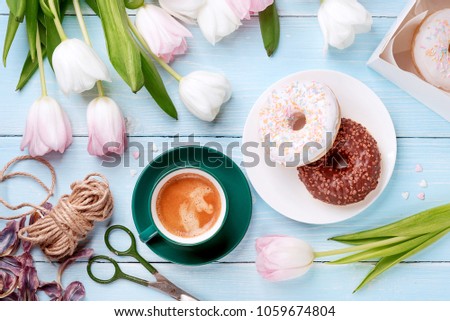donuts, coffee and tulips on a blue wooden background. breakfast in summer with family.