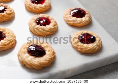 Tasty cookies with jam on stone board