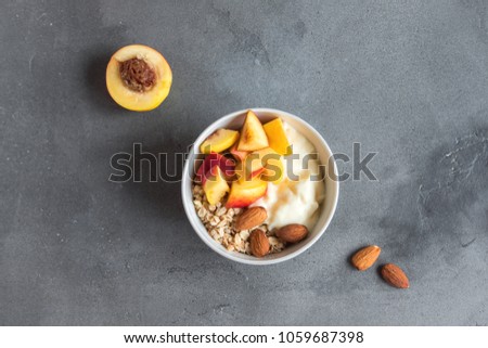 Homemade oatmeal granola with yogurt and peaches in bowl for healthy breakfast. Cereal granola and fruit breakfast bowl with yogurt.