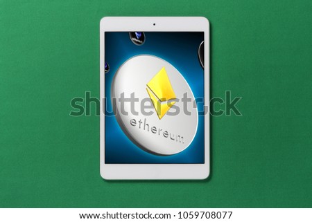 White tablet computer isolated on over green background with ethereum on screen