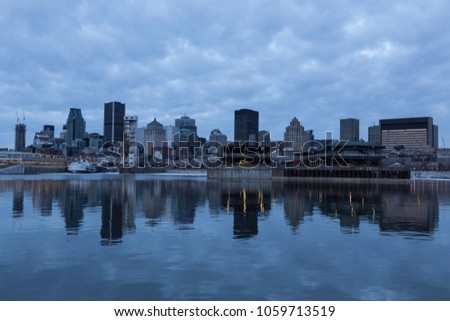 Montreal downtown skyline reflected in the St. Lawrence river at the early morning blue hour with clouds, Quebec, Canada
